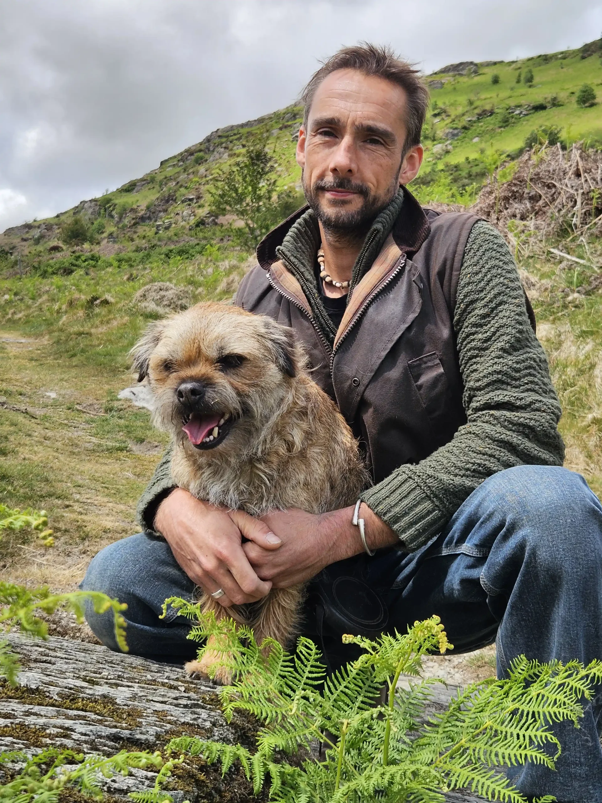 Man with a small dog outdoors on hillside